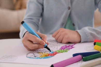 Photo of Child coloring drawing at table in room, closeup