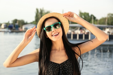 Photo of Beautiful young woman wearing stylish sunglasses near river