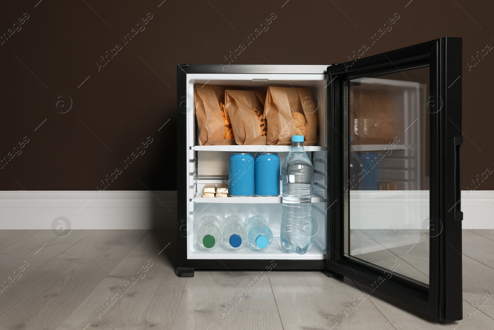 Photo of Mini bar filled with food and drinks near brown wall indoors