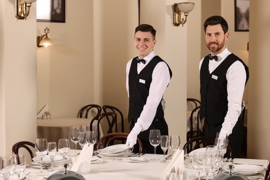 Men setting table in restaurant. Professional butler courses