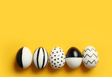 Painted Easter eggs on color background, top view with space for text