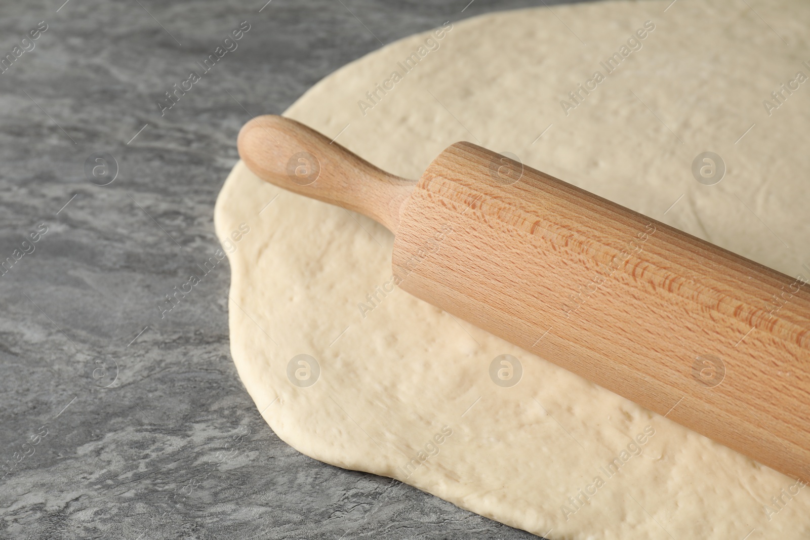 Photo of Raw dough and rolling pin on grey table