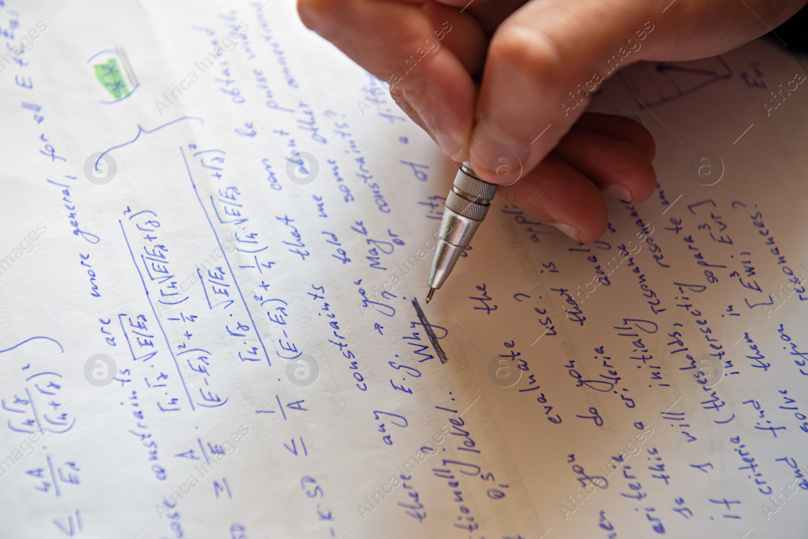 Photo of Student writing mathematical calculations on paper, closeup