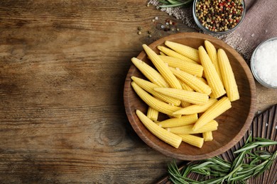 Photo of Fresh baby corn cobs and spices on wooden table, flat lay. Space for text