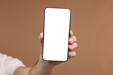 Photo of Man showing smartphone on light brown background, closeup. Mockup for design