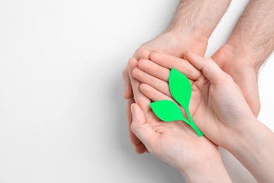 Photo of People holding paper green plant on white background, top view. Corporate social responsibility concept