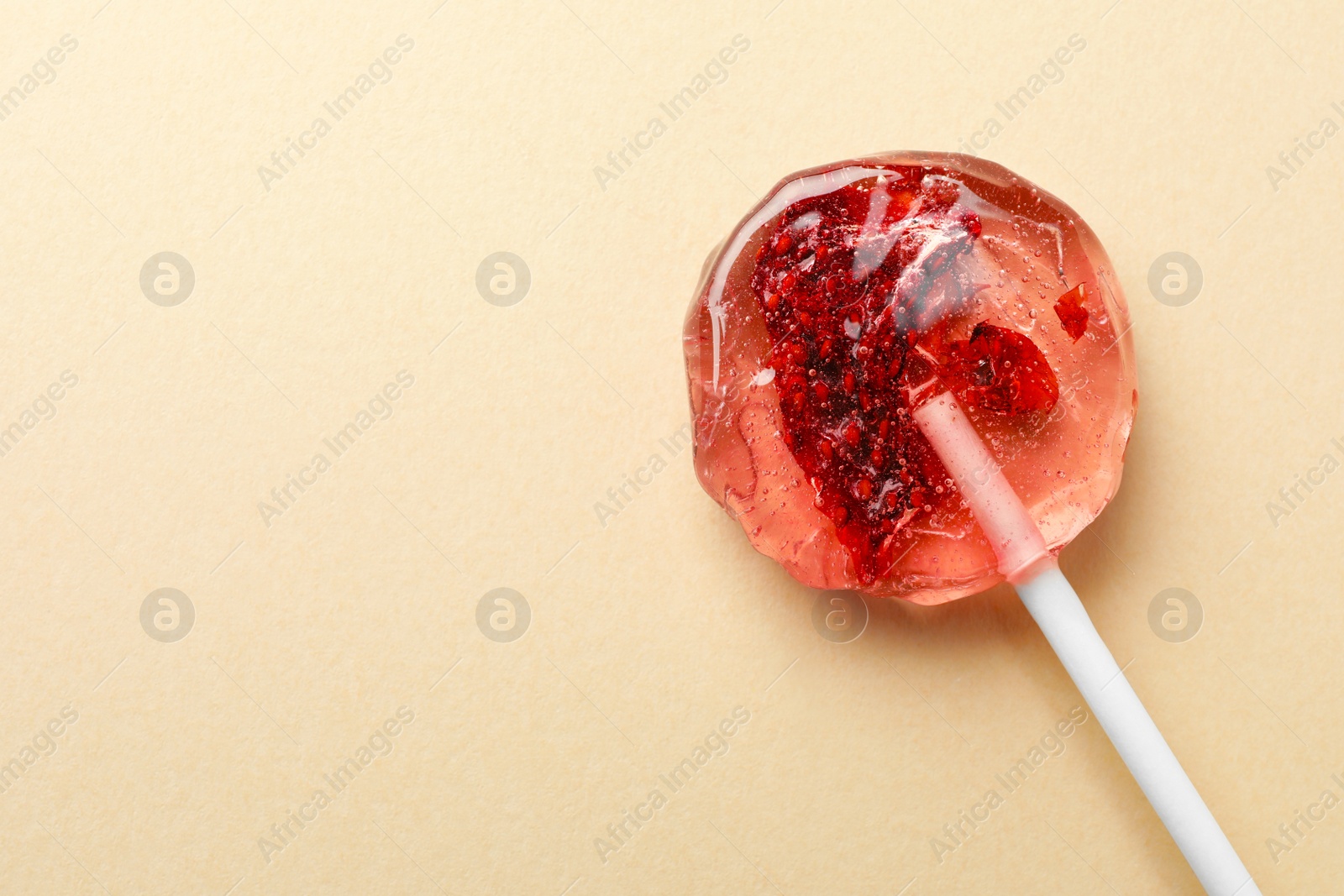 Photo of Sweet colorful lollipop with berries on beige background, top view. Space for text