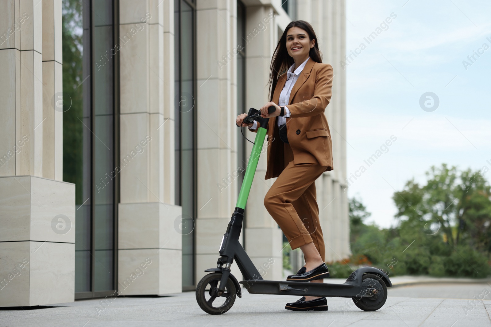 Photo of Businesswoman with modern electric kick scooter on city street