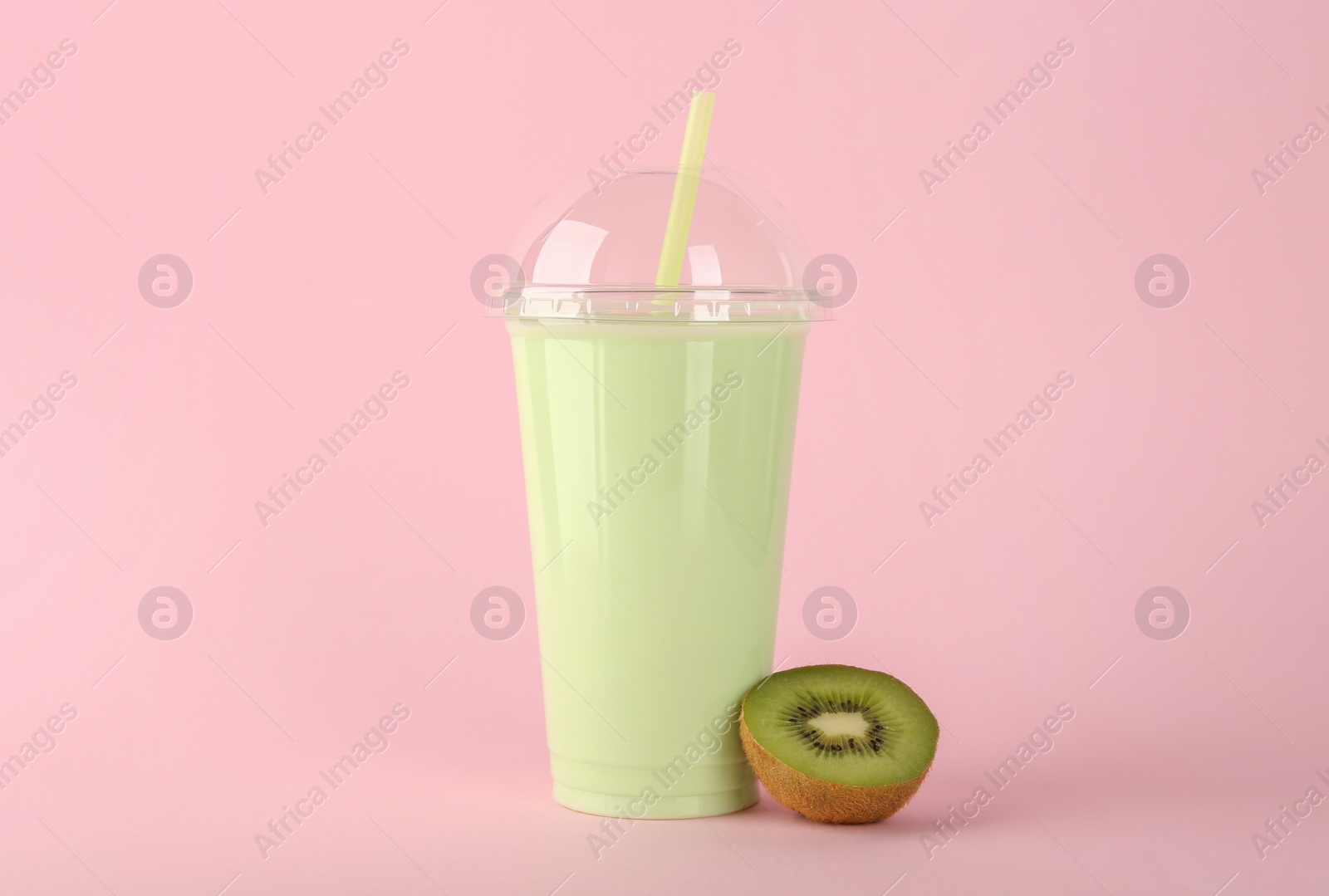 Photo of Plastic cup of tasty smoothie and fresh kiwi on pink background