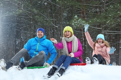 Photo of Happy family sledding in forest on snow day