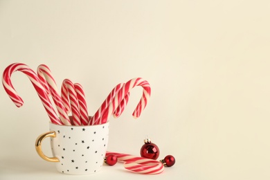 Photo of Candy canes and Christmas balls on beige background, space for text