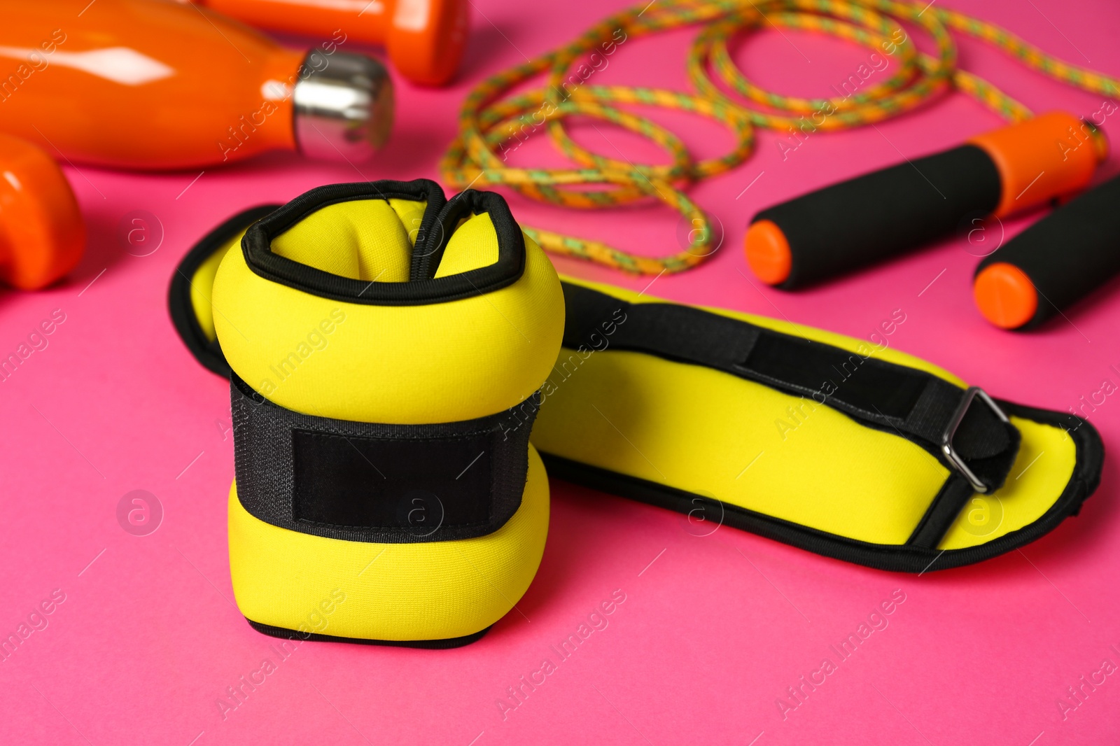 Photo of Yellow weighting agents and sport equipment on pink background