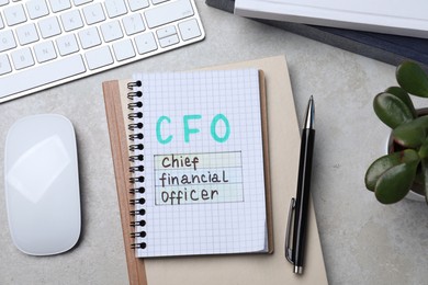 Photo of Notebook with CFO abbreviation on grey office table, flat lay. Financial management