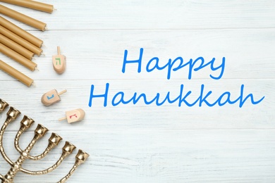 Image of Happy Hanukkah. Traditional menorah, candles and dreidels on white wooden table, flat lay 