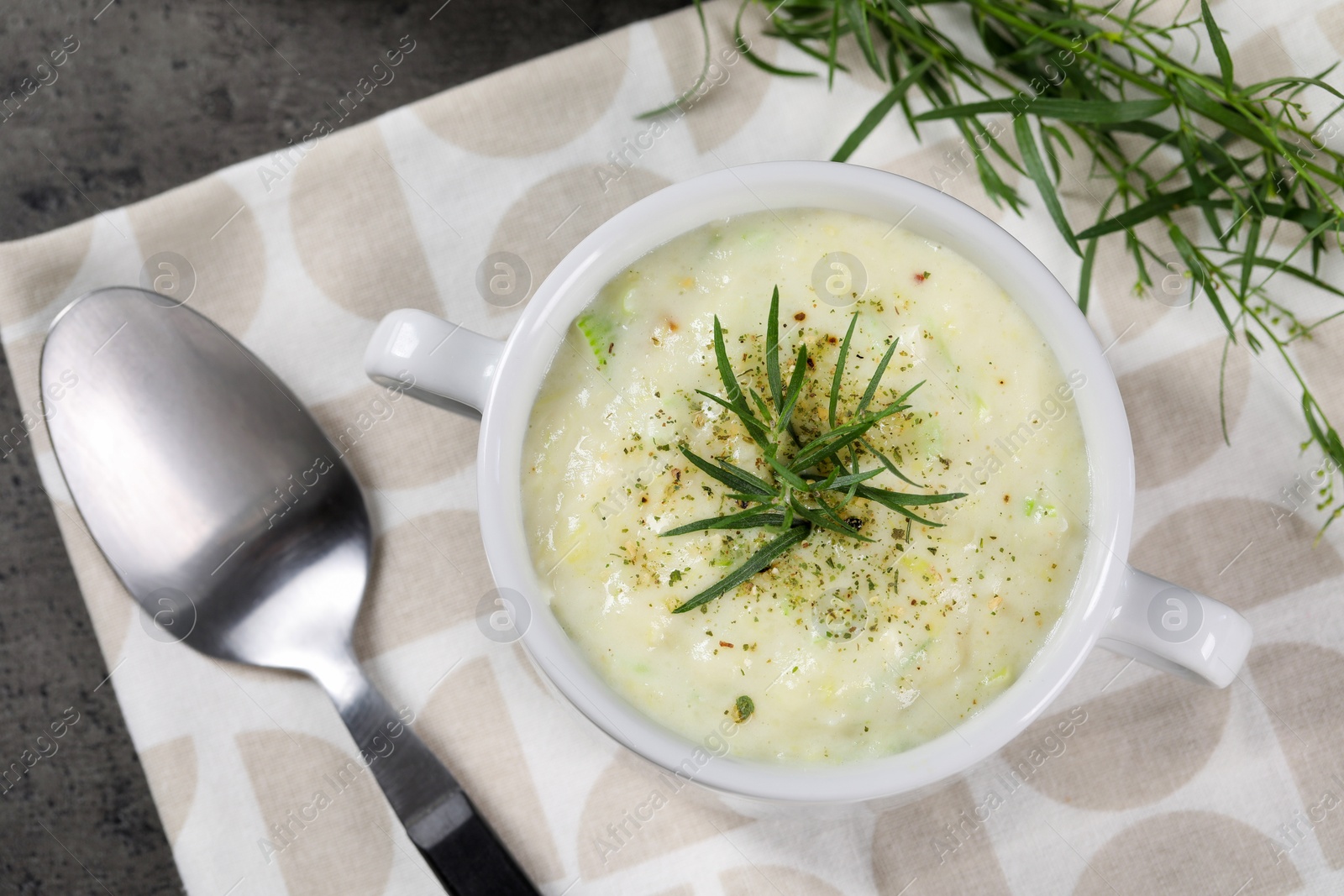 Photo of Delicious cream soup with tarragon, spices and potato in bowl on table, top view