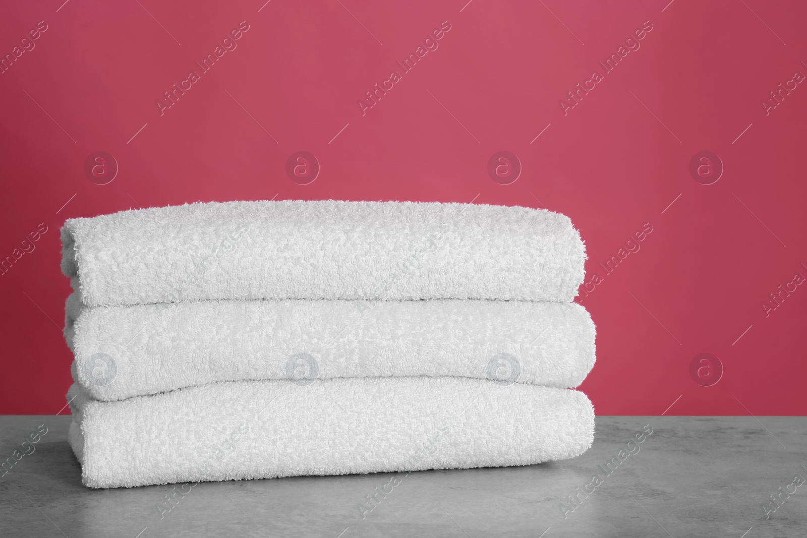 Photo of Stack of fresh towels on light grey stone table, closeup