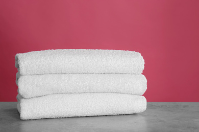 Stack of fresh towels on light grey stone table, closeup