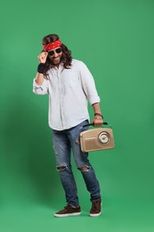 Photo of Stylish hippie man in sunglasses with retro radio receiver on green background
