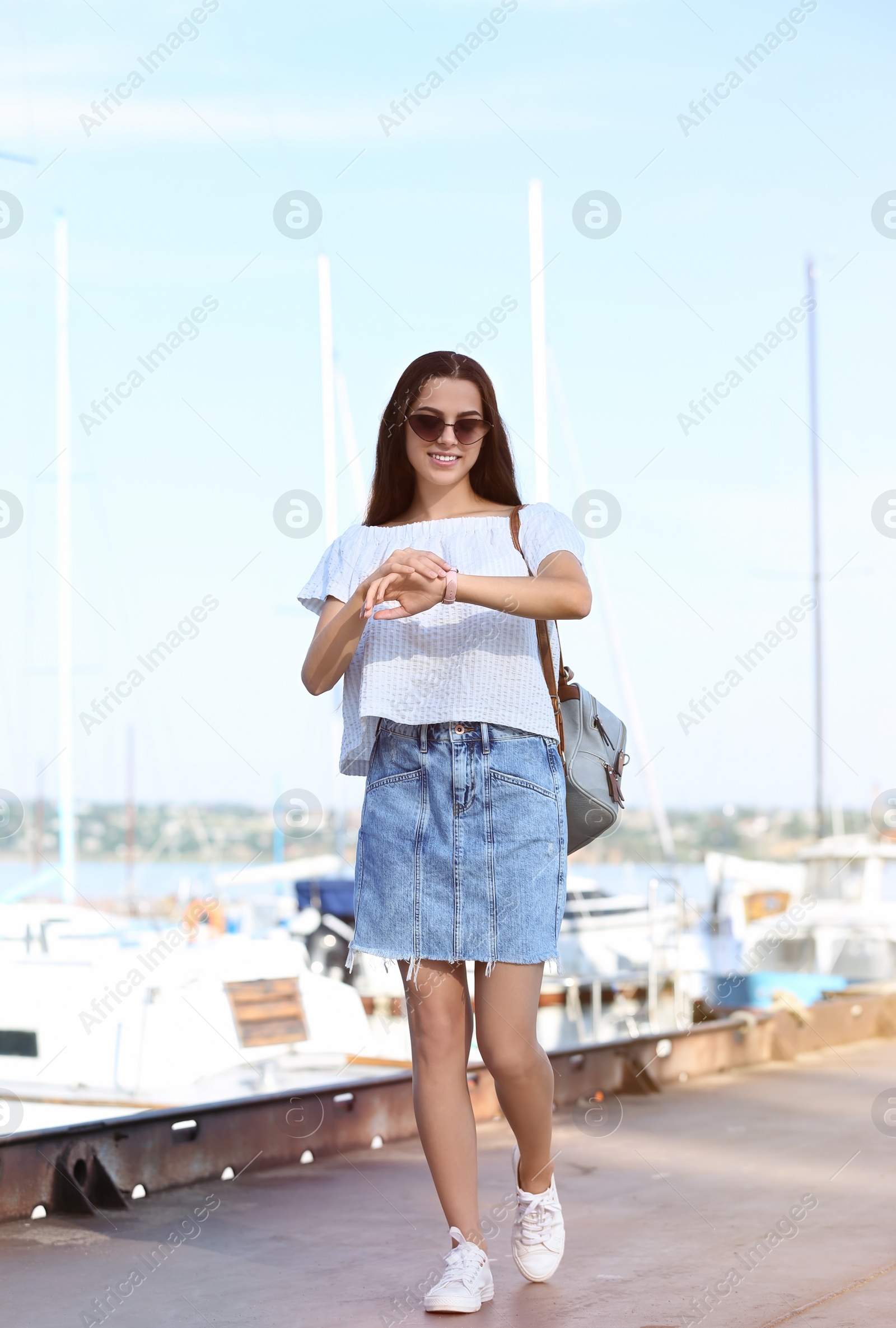 Photo of Young hipster woman in jean skirt on pier