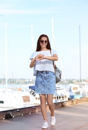 Young hipster woman in jean skirt on pier