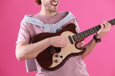 Photo of Young man playing electric guitar on color background, closeup
