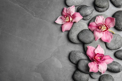 Photo of Zen stones and exotic flowers on dark background, top view with space for text