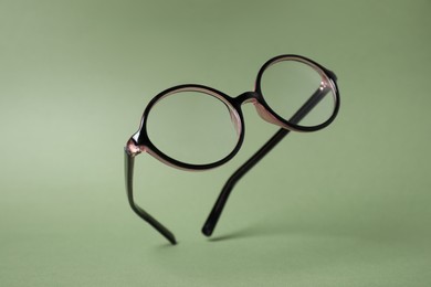 Stylish pair of glasses with plastic frame on olive background
