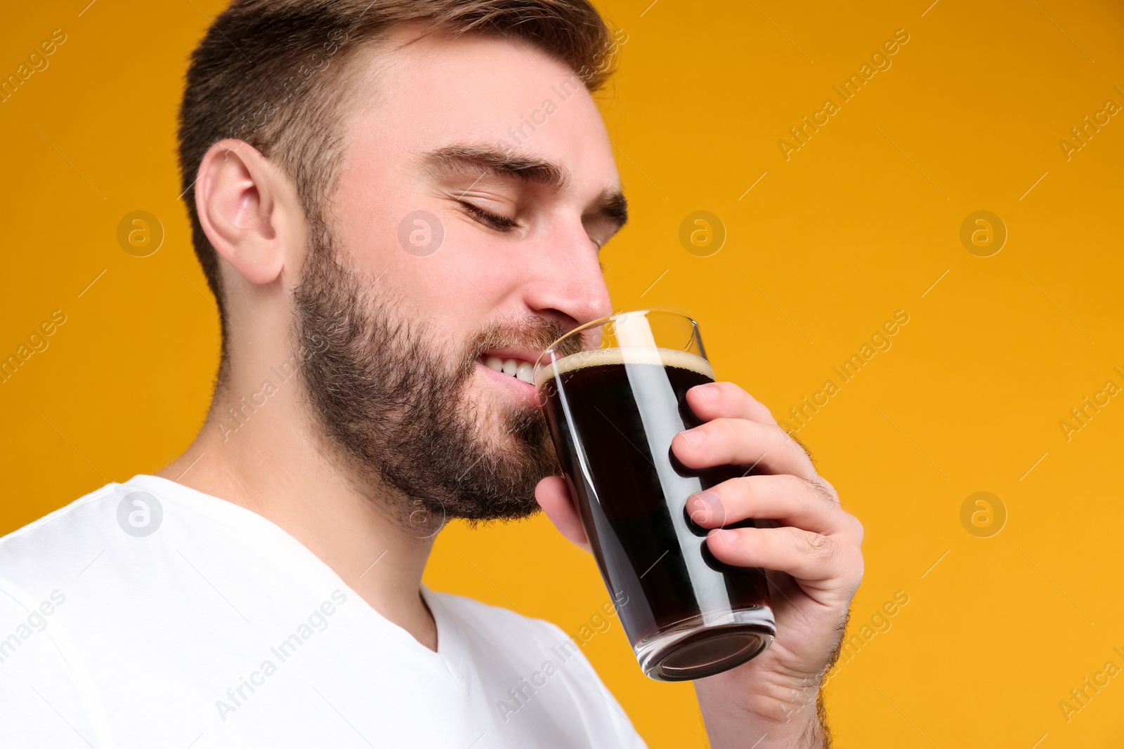 Photo of Handsome man with cold kvass on yellow background. Traditional Russian summer drink