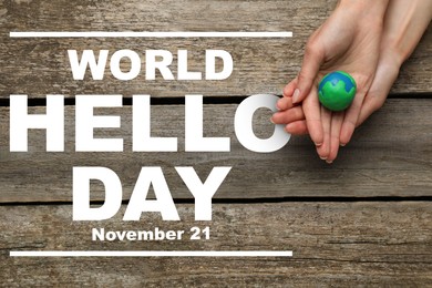 Image of World Hello Day November 21. Woman with plasticine planet at wooden table, top view