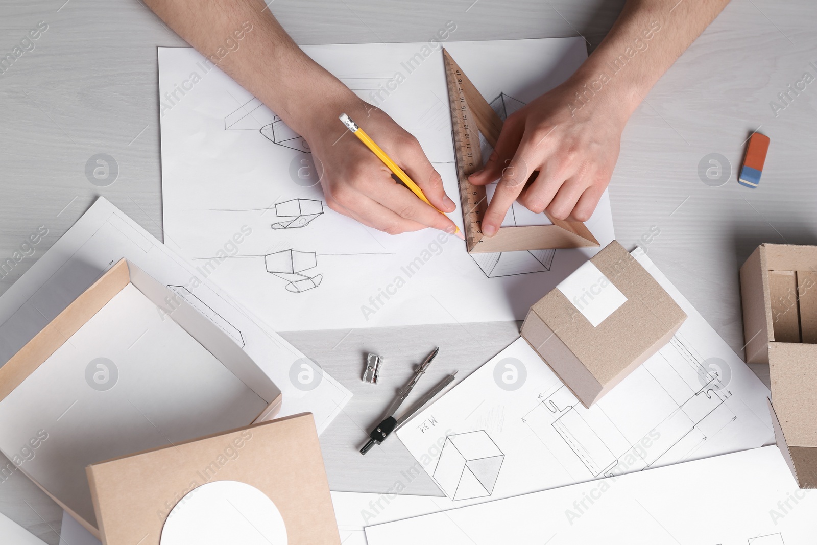 Photo of Man creating packaging design at light wooden table, top view