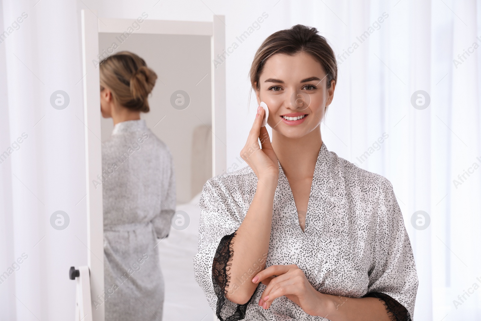 Photo of Beautiful young woman cleaning her face in room