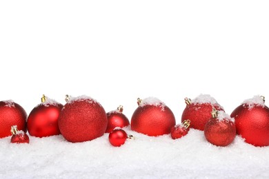 Beautiful red Christmas balls on snow against white background