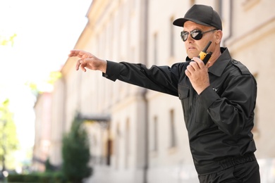 Male security guard using portable radio transmitter outdoors