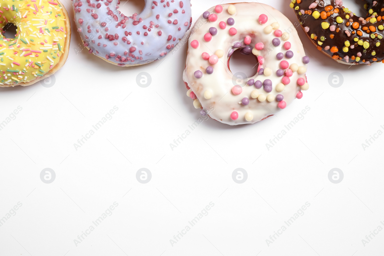 Photo of Delicious glazed donuts on white background, flat lay. Space for text