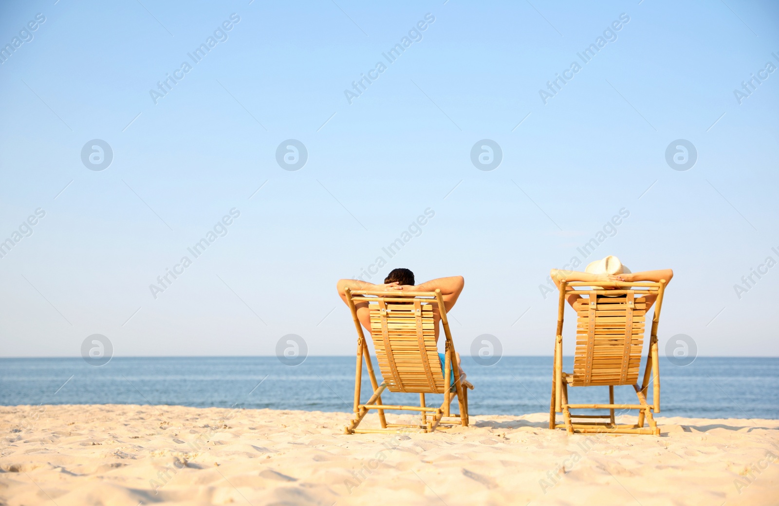 Photo of Couple resting on sunny beach at resort. Space for text