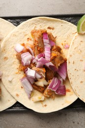 Delicious tacos with vegetables and meat on grey textured table, top view