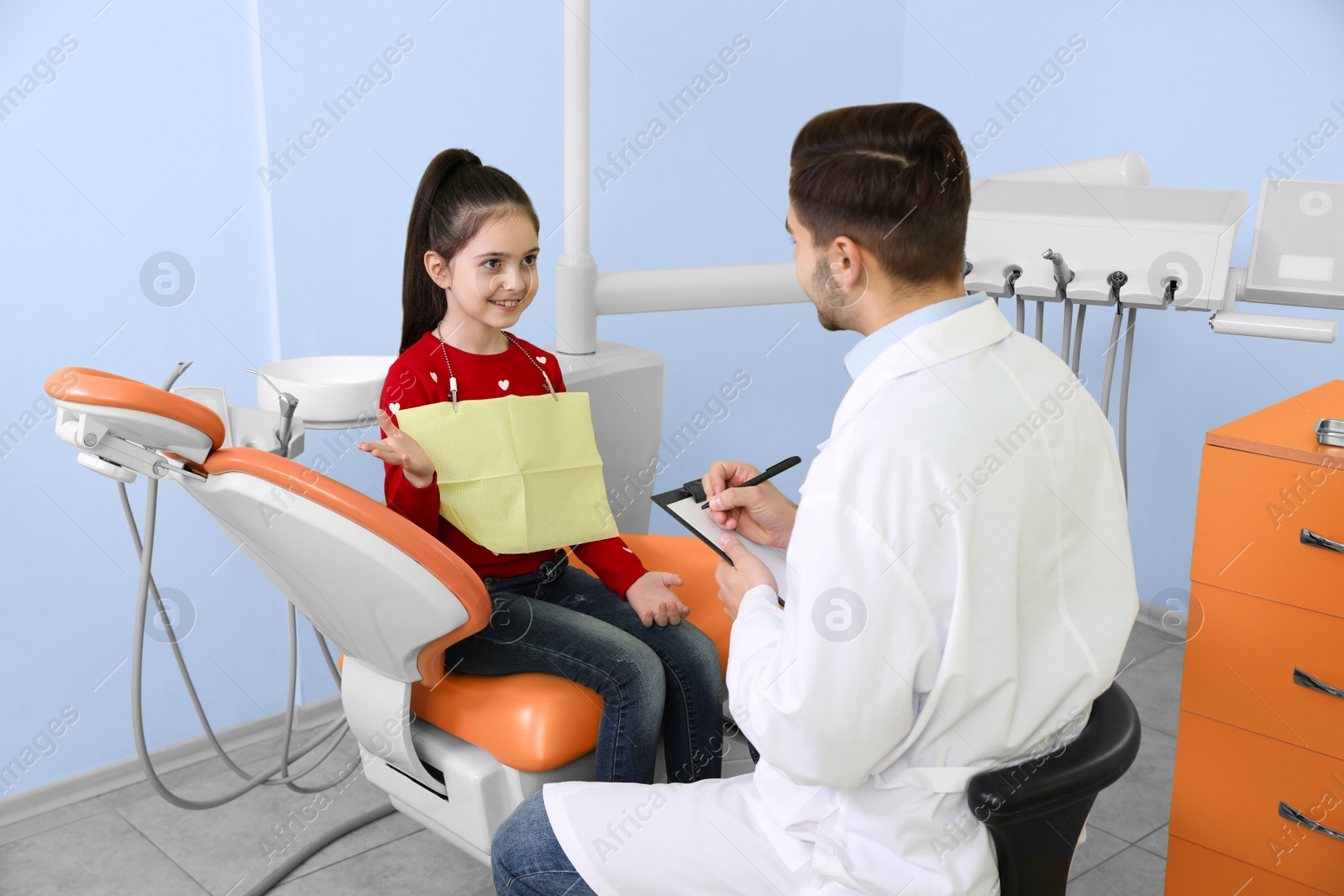 Photo of Professional dentist working with little patient in modern clinic