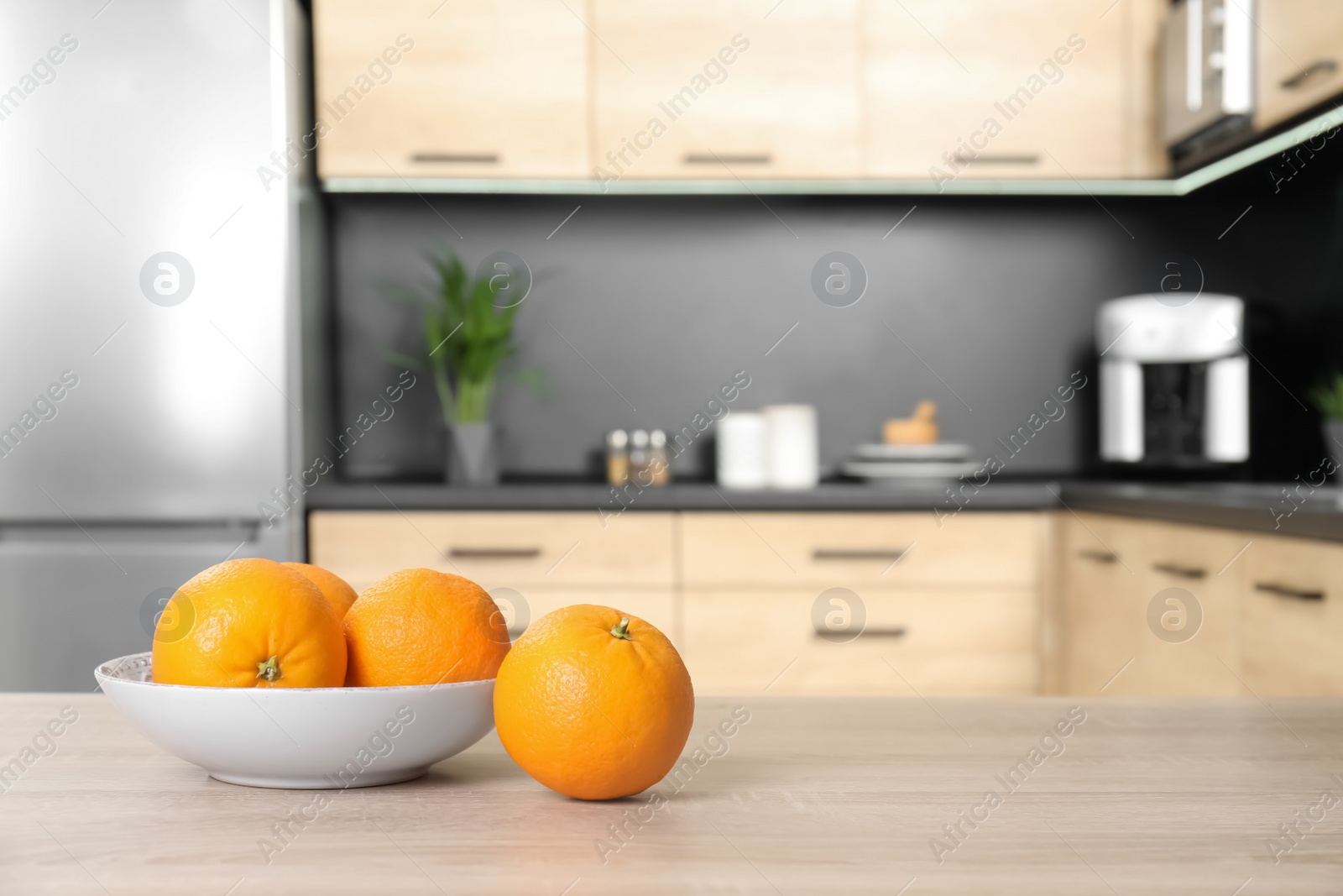 Photo of Fresh oranges on wooden table in kitchen. Space for text