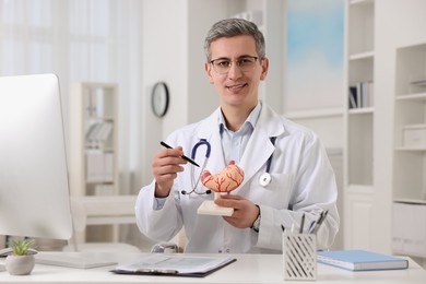 Photo of Gastroenterologist showing human stomach model at table in clinic
