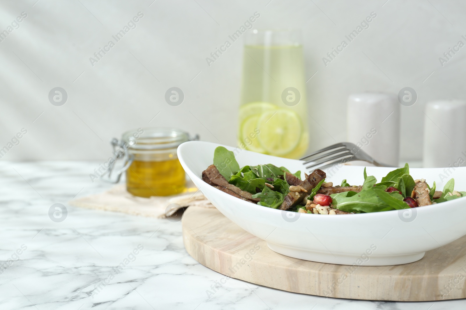Photo of Delicious salad with beef tongue, arugula, seeds and fork served on white marble table. Space for text