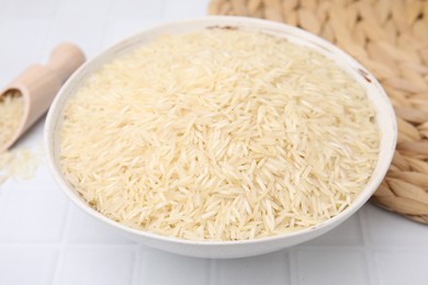 Photo of Raw rice in bowl on white tiled table, closeup
