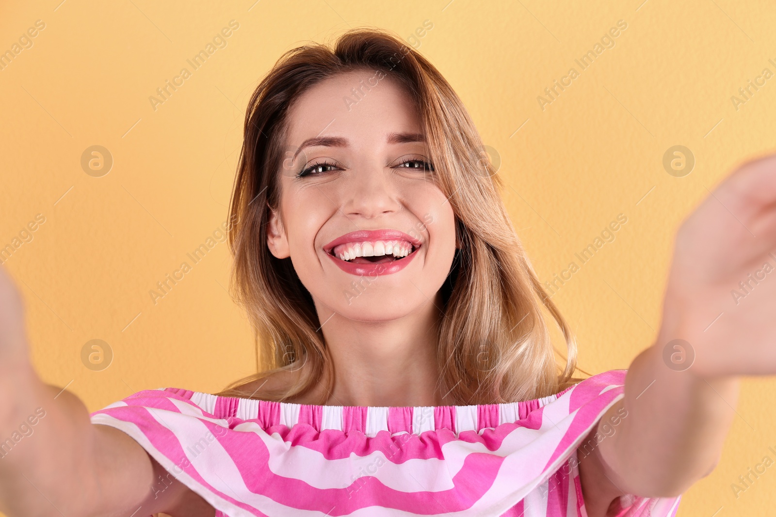 Photo of Beautiful laughing woman taking selfie on color background