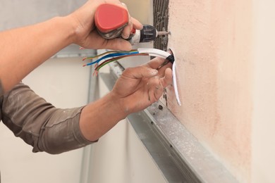 Photo of Worker installing socket in tile indoors, closeup