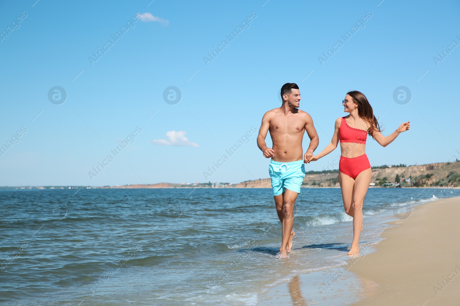 Photo of Woman in bikini and her boyfriend on beach, space for text. Happy couple