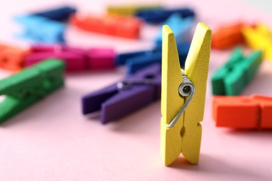 Yellow clothespin standing among lying ones on pink background. Diversity concept