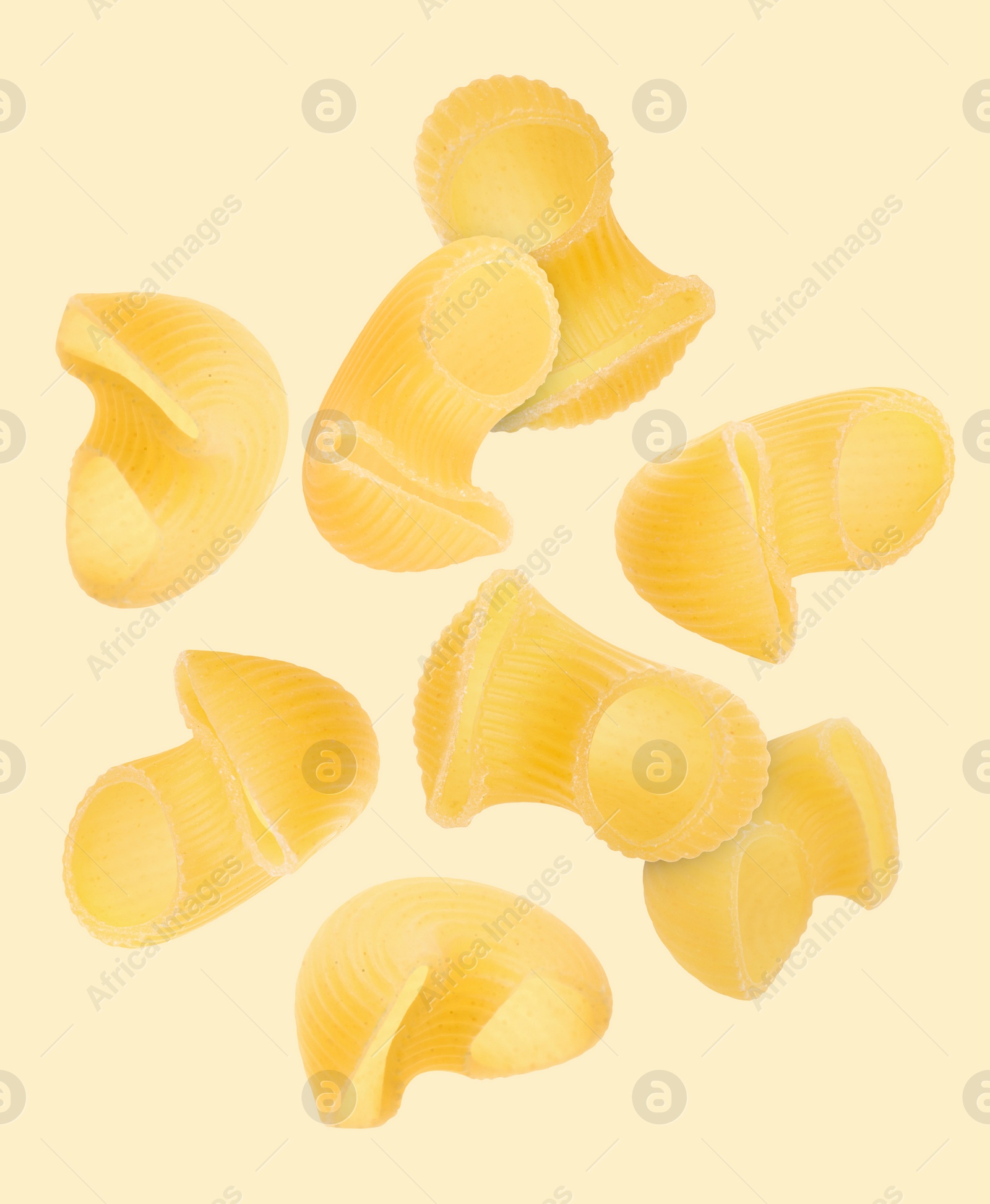 Image of Raw horns pasta flying on beige background