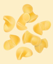 Raw horns pasta flying on beige background