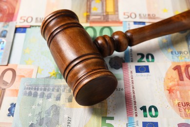 Photo of Tax law. Wooden gavel on euro banknotes, closeup
