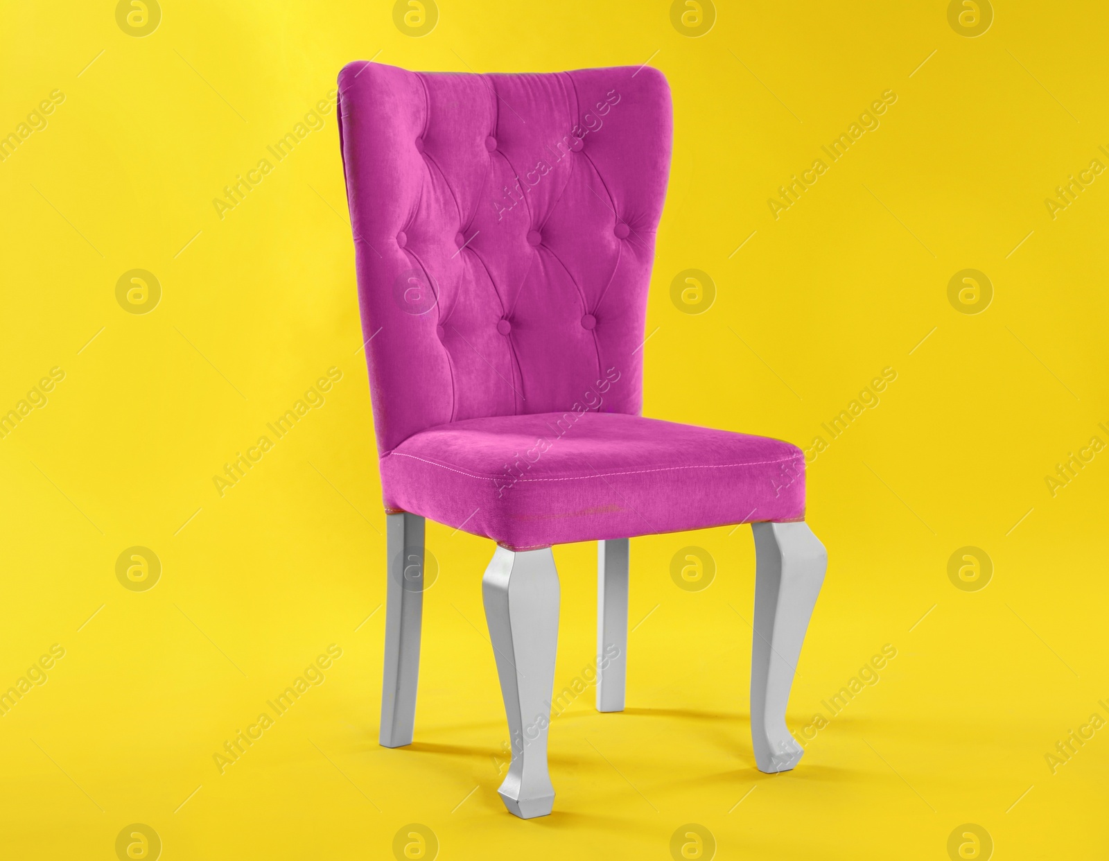 Photo of Stylish pink chair on yellow background. Element of interior design