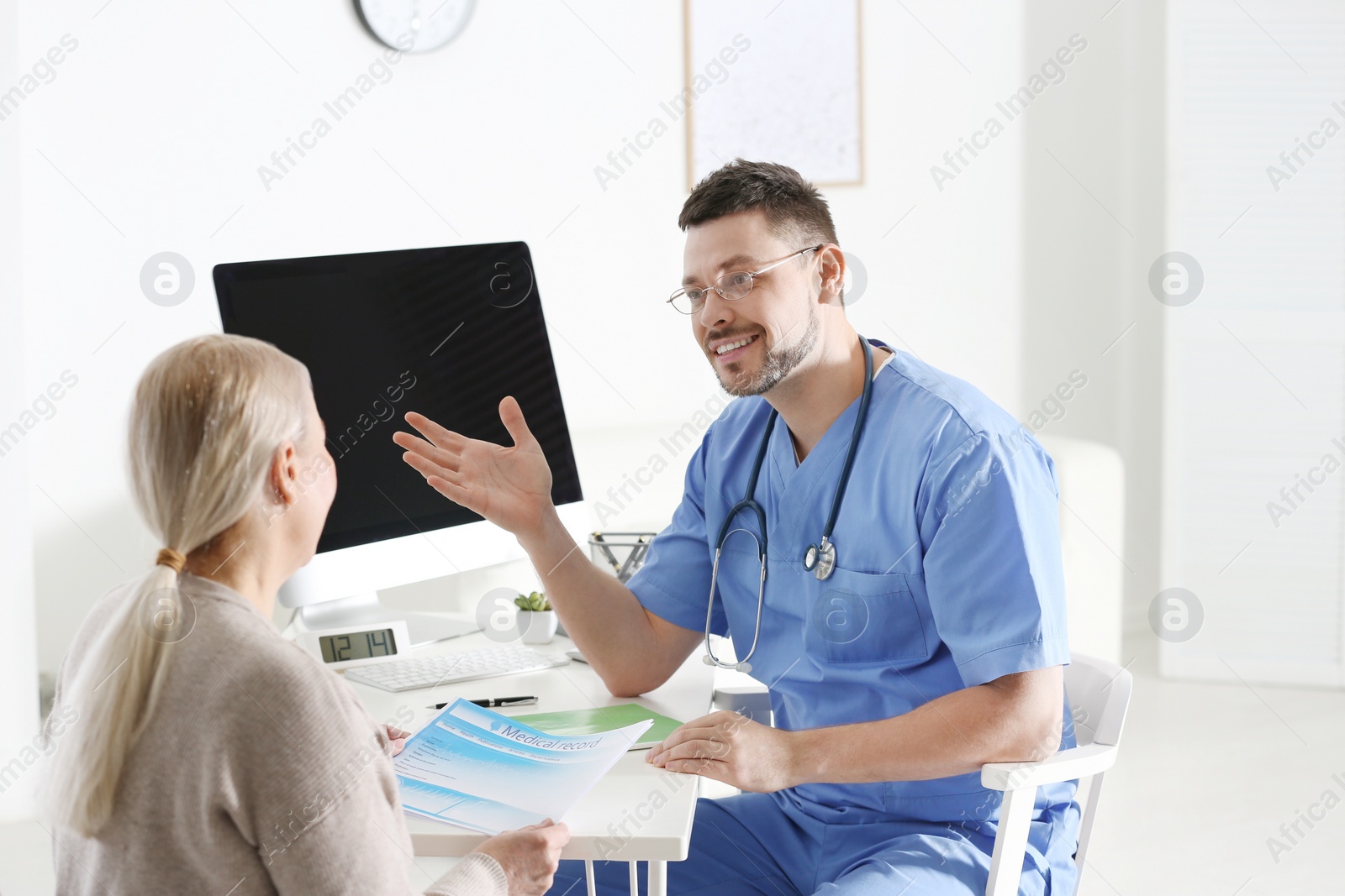 Photo of Doctor consulting patient at desk in clinic